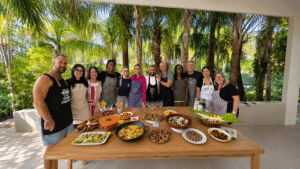 Grupo de participantes sonrientes alrededor de una mesa con platos saludables preparados durante un taller culinario