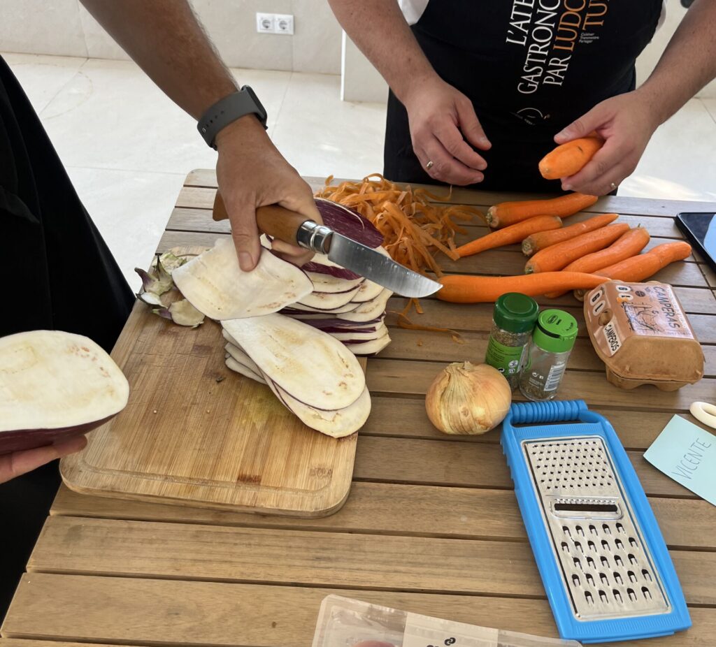 Participantes preparando ingredientes frescos durante un taller culinario guiado sobre alimentación saludable, organización de comidas y bienestar.
